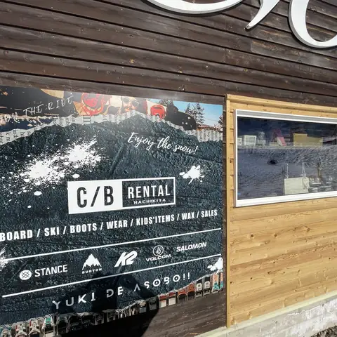 黒いコンクリート調の看板。破れた紙のような縁取りの中にC/B RENTALのロゴ、取扱品目、ブランドロゴ、YUKI DE ASOBO!!の文字