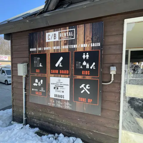 木目調の看板。SKI、SNOW BOARD、KIDS、SALES、BRANDS、TUNE UPの6つの枠にアイコンと文字を配置し、下に営業時間を記載